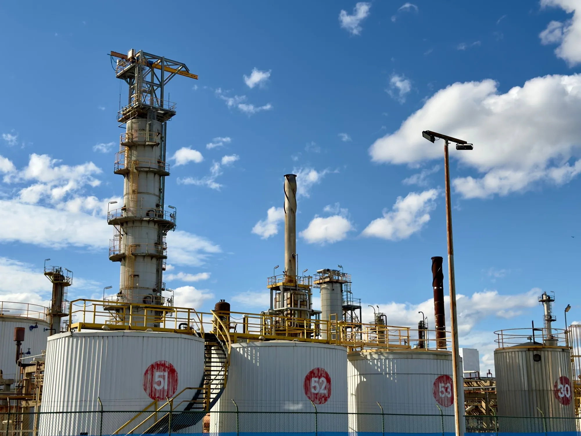 Fuel storage tanks and refinery towers under a blue sky
